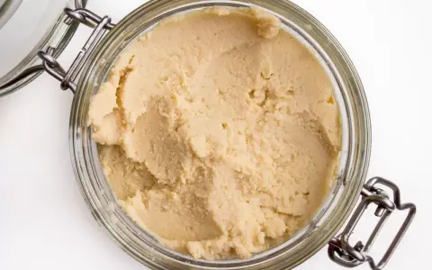 Słoik z domowym hummusem. Zastanawiasz się, czy można mrozić hummus? Tak, można go zamrozić, by dłużej zachował świeżość.