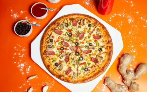 Chrupiąca pizza z pieczarkami, salami i papryką na pomarańczowym tle.