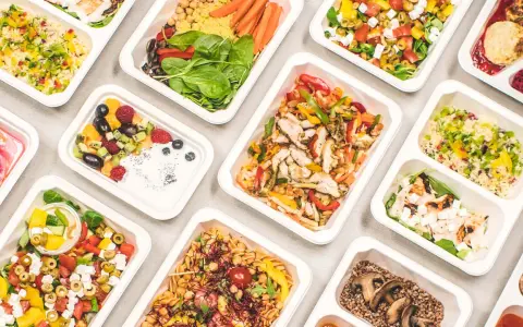 Catering dietetyczny co to? Różnorodne, zdrowe posiłki w wygodnych pojemnikach: sałatki, dania z kurczakiem, kaszą, owocami i warzywami.