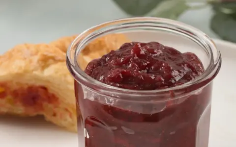 Słoiczek z konfiturą z płatków róży obok ciastka.