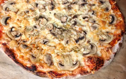 Pyszna pizza capricciosa z pieczarkami i ciągnącym się serem, idealna na szybki obiad.