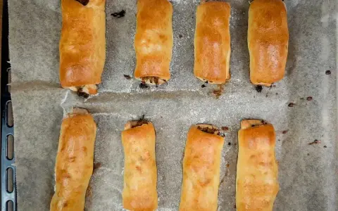 Osiem złotych pasztecików z ciasta francuskiego, idealne ciasto na paszteciki, świeżo upieczonych na papierze do pieczenia.