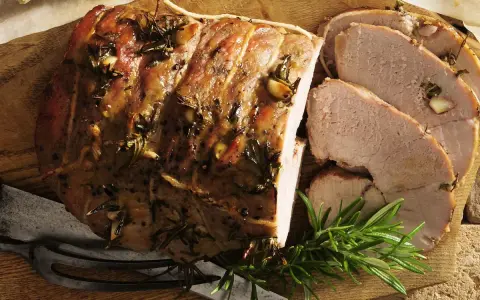 Pieczona jagnięcina co to? Soczysty, aromatyczny kawałek mięsa z rozmarynem i czosnkiem, pokrojony w plastry, gotowy do podania.