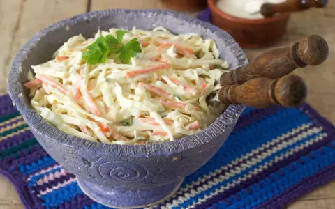 Pyszna surówka z białej kapusty jak w restauracji, z marchewką i majonezem, udekorowana natką pietruszki.