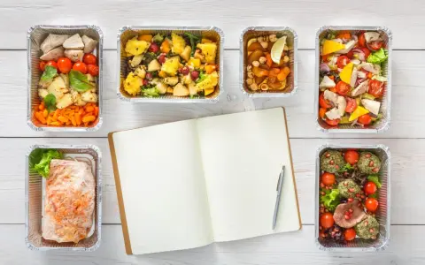 Planujesz catering dietetyczny? Warto! Sześć pudełek z pysznym jedzeniem i notatnik do zapisania celów.