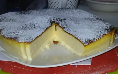 Puszysty sernik z airfryer, oprószony cukrem pudrem, z lekko przypieczoną skórką i kremowym wnętrzem.