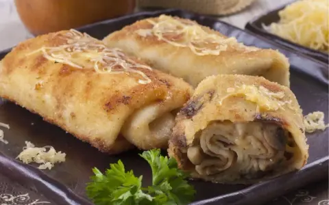 Idealne co na obiad w poniedziałek: złociste krokiety z pieczarkami i serem, posypane startym parmezanem, udekorowane natką pietruszki.
