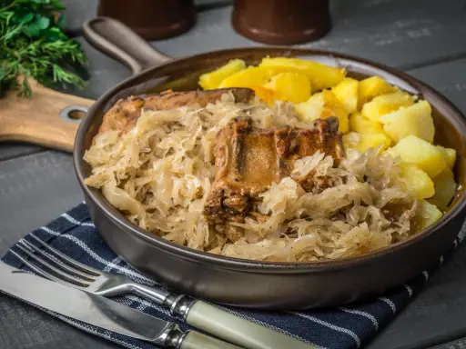 Pyszne żeberka w kapuście kiszonej, idealne do pieczenia w piekarniku. Podane z ziemniakami.