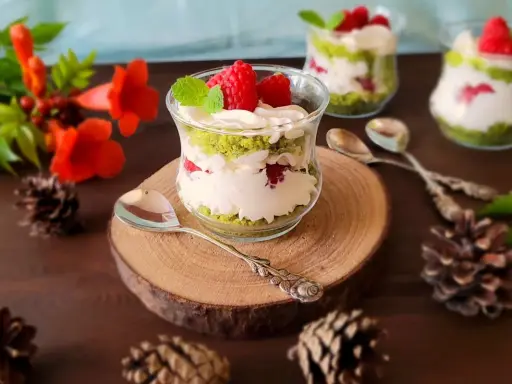 Pyszne ciasto leśny mech na dużą blachę z serkiem mascarpone, podane w szklanych pucharkach, ozdobione malinami i miętą.