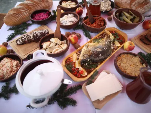 Wigilijny stół pełen smakołyków: karp, pierogi, kapusta, barszcz i chleb. Idealne inspiracje, co ugotować na Wigilię.