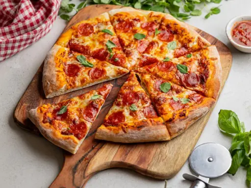 Apetyczna pizza pepperoni z ciągnącym się serem i świeżą bazylią, gotowa do podania.