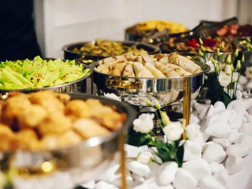 Bufet z jedzeniem: naleśniki, sałatka, smażone kąski. Zastanawiasz się, ile kosztuje catering na imprezę?