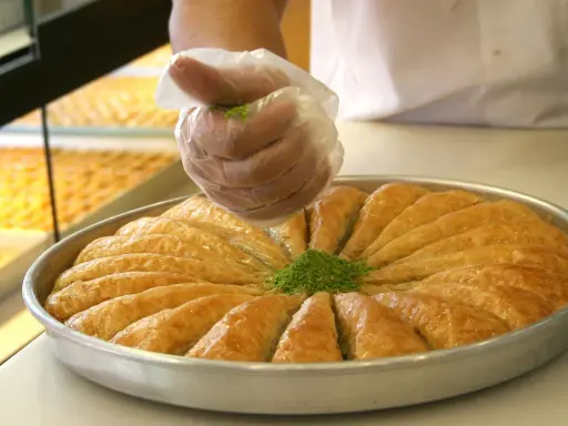 Słodka baklava, co to za przysmak? Warstwy ciasta filo, orzechy i syrop. Posypka z pistacji dodaje uroku.