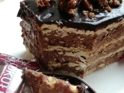 Czekoladowe ciasto bez pieczenia z wafli, idealne na przepis na ciasto kukułka bez pieczenia. Na wierzchu błyszcząca polewa i orzechy.