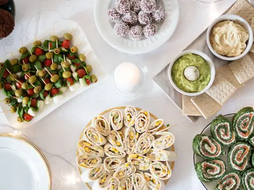 Stół z przekąskami: koreczki caprese, roladki z tortilli, łososia i szpinaku, dipy, ciasteczka.