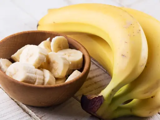 Banan wartości odżywcze: pyszne, żółte banany obok miseczki z pokrojonymi plasterkami. Idealne na zdrową przekąskę.