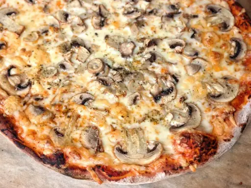 Pyszna pizza capricciosa z pieczarkami i ciągnącym się serem, idealna na szybki obiad.