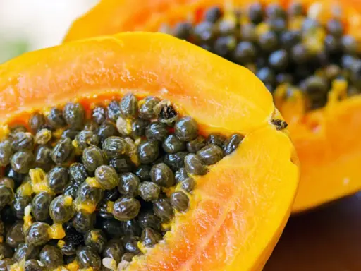 Dwa soczyste kawałki papaya z mnóstwem czarnych nasion w środku.