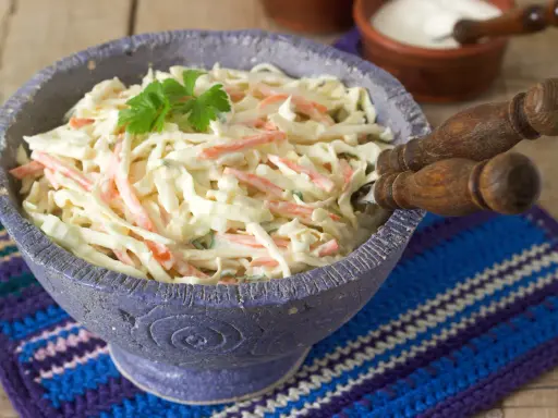 Pyszna surówka z białej kapusty jak w restauracji, z marchewką i majonezem, udekorowana natką pietruszki.