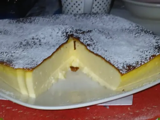 Puszysty sernik z airfryer, oprószony cukrem pudrem, z lekko przypieczoną skórką i kremowym wnętrzem.