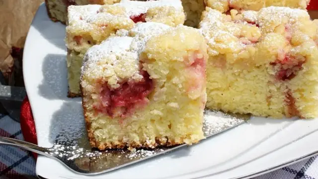 Szybkie ciasto z truskawkami, posypane cukrem pudrem, na białym talerzu. Idealne na letnie popołudnie.