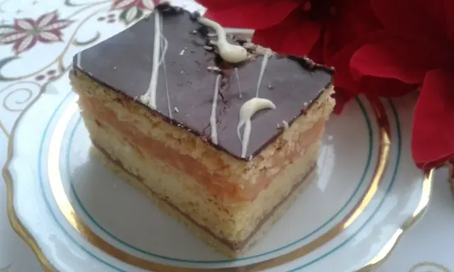 Pyszny kawałek ciasta z warstwami biszkoptu, kremu serowego i jabłek, oblany czekoladą. Idealny na przepis na ciasto delicja z serem i jabłkami.