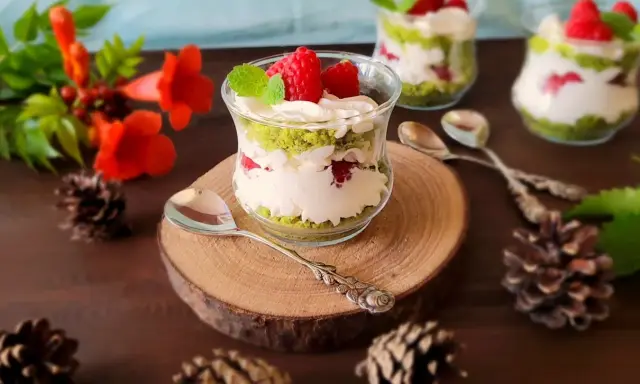 Pyszne ciasto leśny mech na dużą blachę z serkiem mascarpone, podane w szklanych pucharkach, ozdobione malinami i miętą.