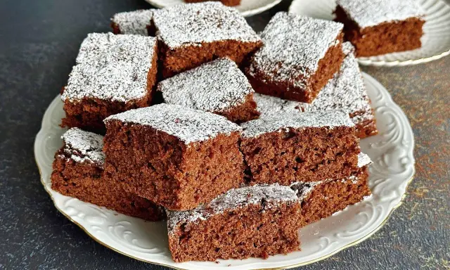 Pyszne, wilgotne ciasto czekoladowe pokrojone w kostkę, posypane cukrem pudrem. Idealne na przepis na ciasto kręcone.