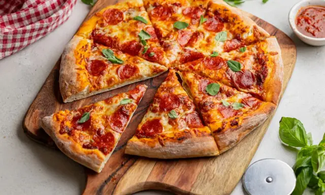 Apetyczna pizza pepperoni z ciągnącym się serem i świeżą bazylią, gotowa do podania.