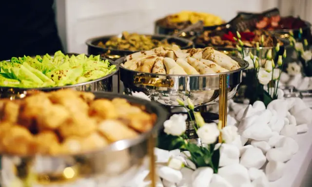Bufet z jedzeniem: naleśniki, sałatka, smażone kąski. Zastanawiasz się, ile kosztuje catering na imprezę?