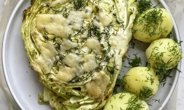 Pieczona młoda kapusta z serem i koperkiem, podana z młodymi ziemniakami. Idealny pomysł, co zrobić z młodej kapusty na obiad.