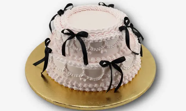 Dwupiętrowy tort w kolorze pudrowego różu, ozdobiony czarnymi wstążkami. Idealny na osiemnastkę, zastanawiasz się, ile kosztuje catering na 18?