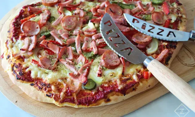 Pyszna pizza z kiełbasą i warzywami, gotowa do pokrojenia. To najlepsza pizza przepis, jaki kiedykolwiek próbowałeś!