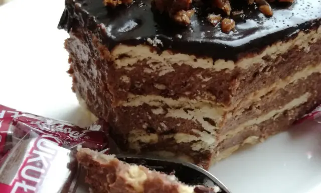 Czekoladowe ciasto bez pieczenia z wafli, idealne na przepis na ciasto kukułka bez pieczenia. Na wierzchu błyszcząca polewa i orzechy.