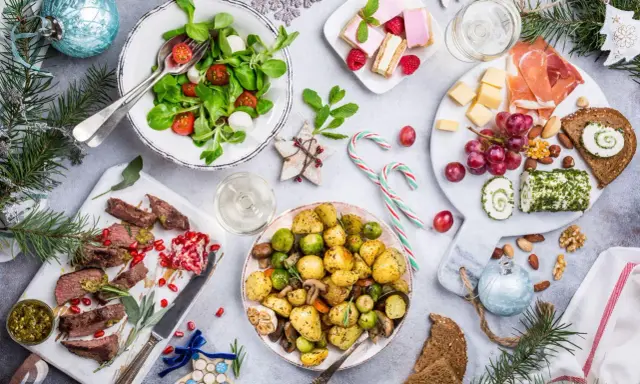 Wigilia na talerzu: pieczone ziemniaki, mięso, sałatka, ser, słodkości. Zastanawiasz się, ile kosztuje catering na wigilię?