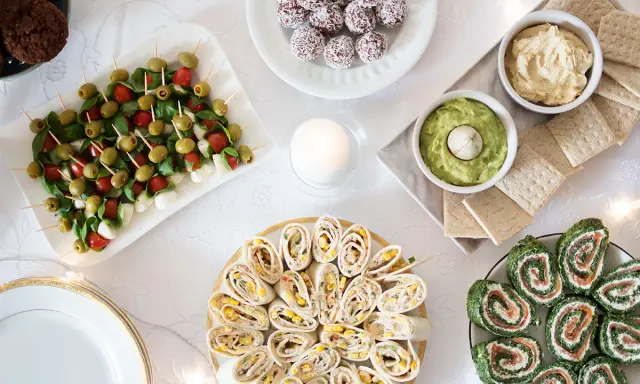 Stół z przekąskami: koreczki caprese, roladki z tortilli, łososia i szpinaku, dipy, ciasteczka.