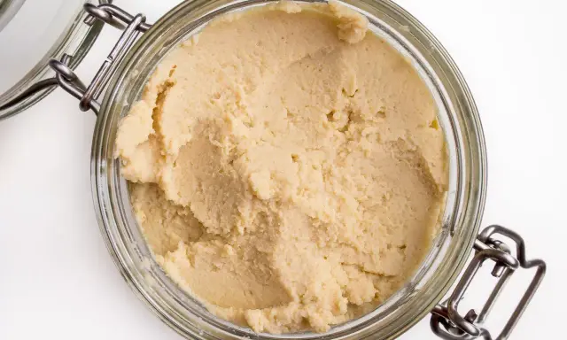 Słoik z domowym hummusem. Zastanawiasz się, czy można mrozić hummus? Tak, można go zamrozić, by dłużej zachował świeżość.