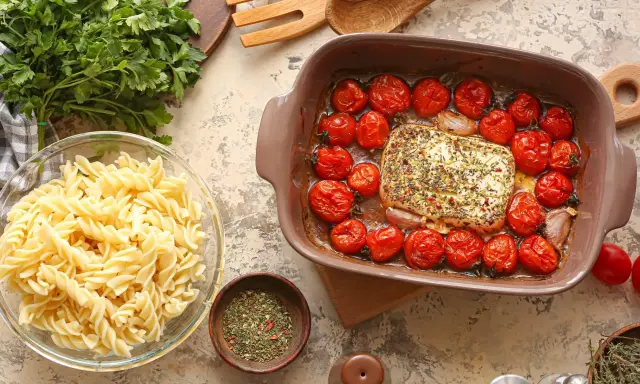 Pieczenie sera feta z pomidorkami koktajlowymi to świetny pomysł na obiad. Obok makaron fusilli i świeża natka.