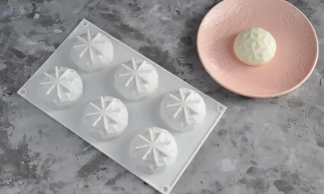 Forma silikonowa z sześcioma wypukłymi ciastkami, idealna do przepisu na ciasto do formy silikonowej. Jedno ciastko na różowym talerzyku.