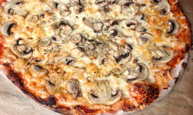 Pyszna pizza capricciosa z pieczarkami i ciągnącym się serem, idealna na szybki obiad.