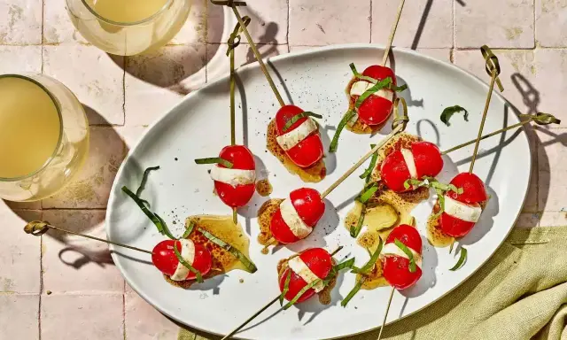 Szabli z pomidorkami koktajlowymi, mozzarellą i bazylią na białym talerzu.