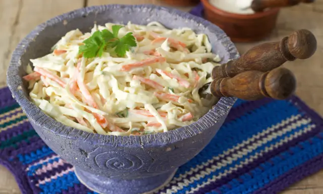 Pyszna surówka z białej kapusty jak w restauracji, z marchewką i majonezem, udekorowana natką pietruszki.