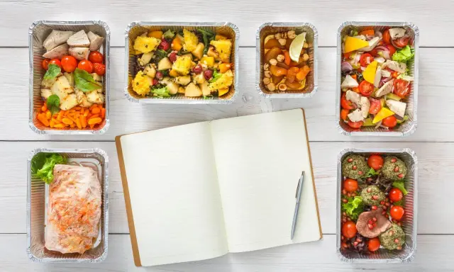 Planujesz catering dietetyczny? Warto! Sześć pudełek z pysznym jedzeniem i notatnik do zapisania celów.