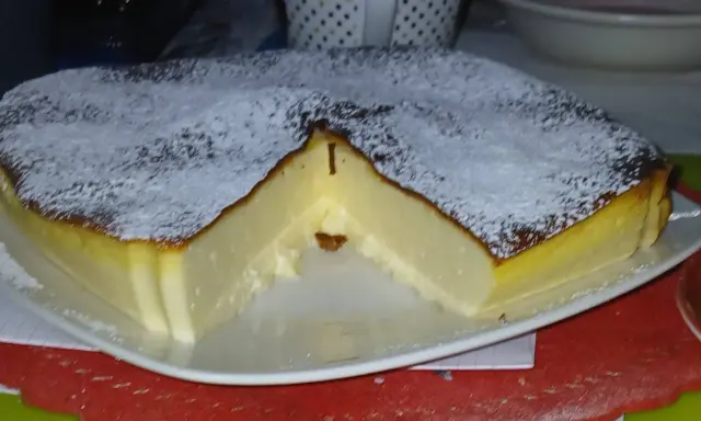 Puszysty sernik z airfryer, oprószony cukrem pudrem, z lekko przypieczoną skórką i kremowym wnętrzem.