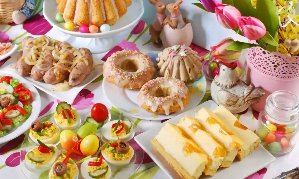 Wielkanocne potrawy: babka, kiełbaski, jajka faszerowane, sernik i słodkie przekąski.