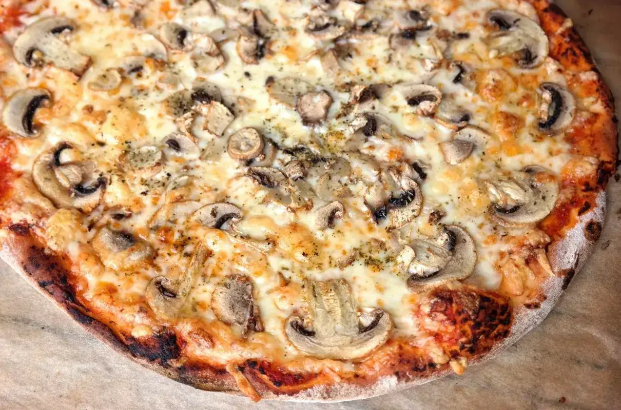 Pyszna pizza capricciosa z pieczarkami i ciągnącym się serem, idealna na szybki obiad.