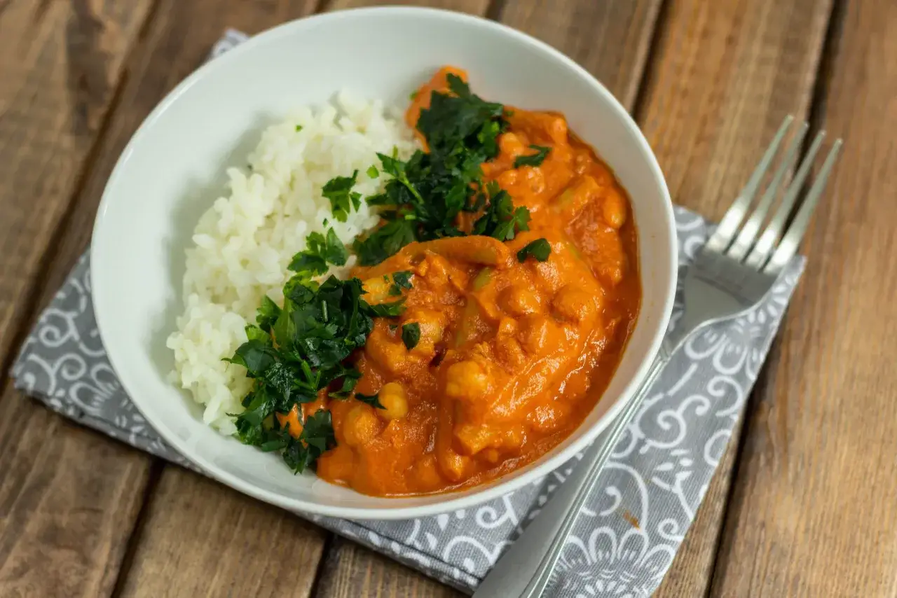 Pyszne danie co na obiad bez mięsa: ryż z kremowym curry z ciecierzycy, posypane świeżą natką pietruszki.