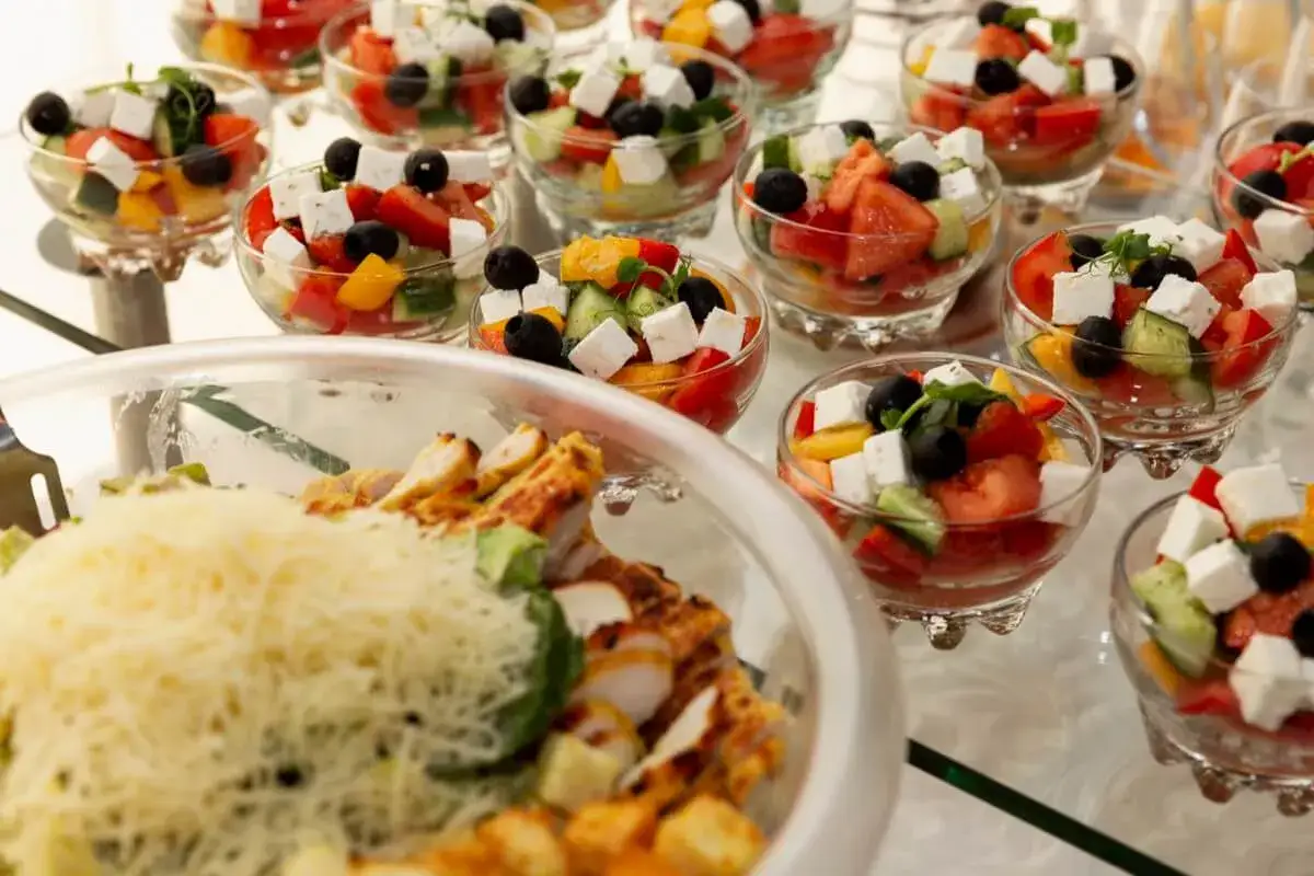 Kolorowe sałatki w pucharkach i danie z kurczakiem. Idealne na imprezę, gdzie można zamówić catering.