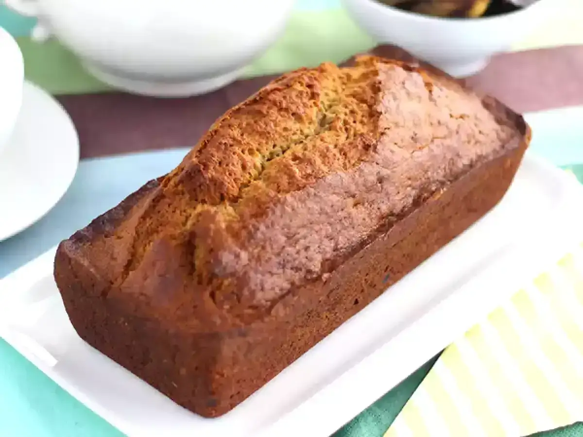 Apetyczny chleb bananowy na białej paterze, gotowy do pokrojenia. Idealny na deser lub śniadanie.
