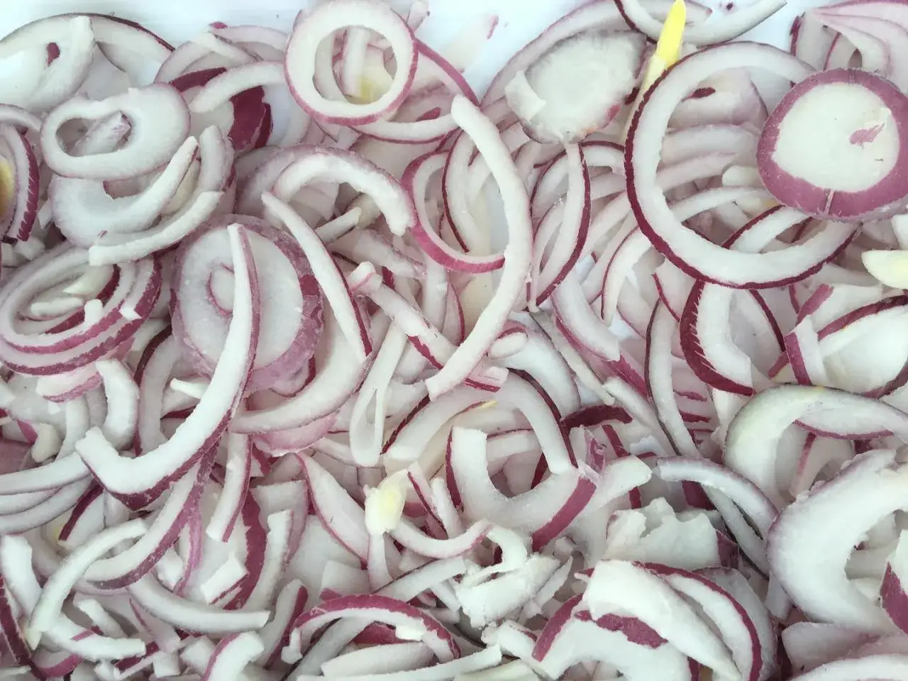 Pokrojona w krążki czerwona cebula, gotowa do mrożenia. Czy można mrozić cebulę? Tak, po pokrojeniu zachowa smak i aromat.